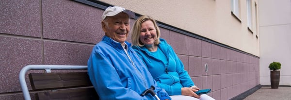 A client and carer sitting and smiling, in matching blue hoodies